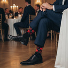 Navy and red argyle groomsmen socks worn with a navy suit and black dress shoes at a wedding reception - Love Sock Company