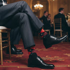 Navy and red argyle dress socks worn with grey trousers and black shoes at a formal event - Love Sock Company