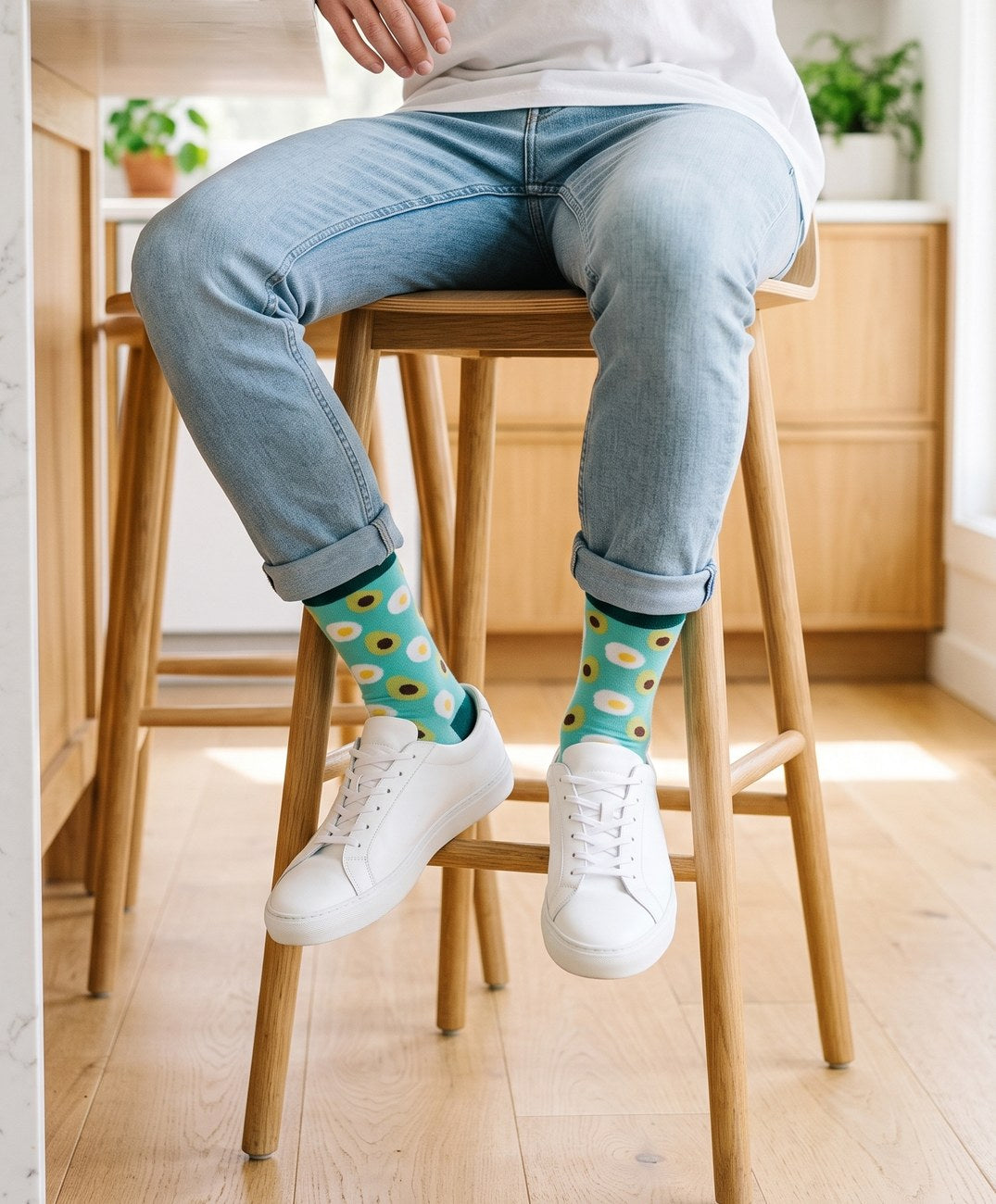 Man on a kitchen stool wearing Love Sock Company Avocado organic cotton crew socks