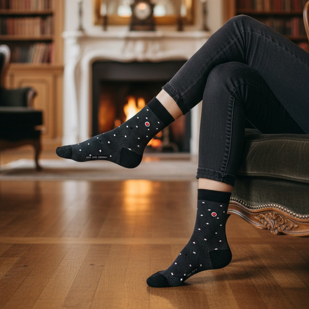 Woman wearing Love Sock Company Polka Night Black organic cotton crew dress socks by a fireplace